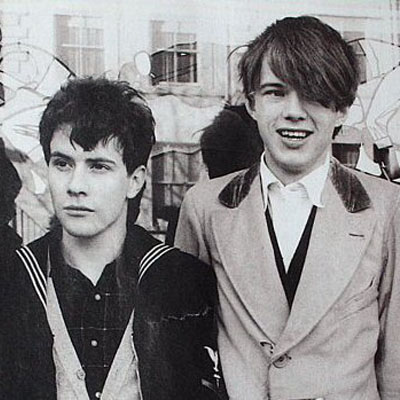 An early  b/w photo of members of the Scottish pop group Orange Juice, featuring a young Edwyn Collins  (right), grinning. 