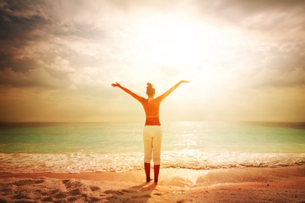 Woman-on-a-beach-greeting-the-morning-sun