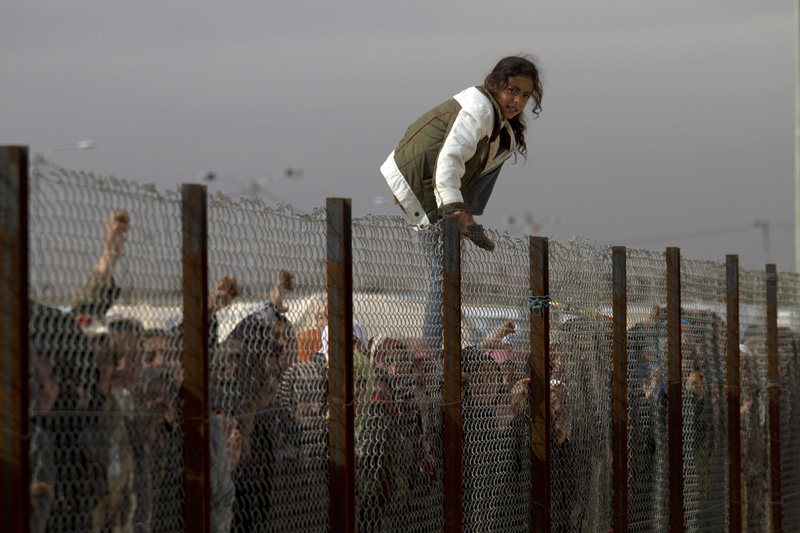 A young Syrian refugee girl jumps the fence as hundreds waited  behind a fence to receive supplies that include food items  at the Za'atri Syrian refugee camp in northern Jordan February 6,2013. ..Jordan  recently announced  that the number of Syrian refugees in the country is expected to exceed 700, 000 in 2013, the state-run Petra news agency reported. (Photo by Heidi Levine/Sipa Press).